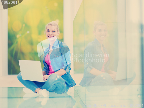 Image of young woman using laptop computer on the floor