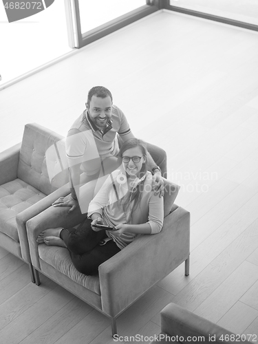 Image of couple relaxing at  home with tablet computers