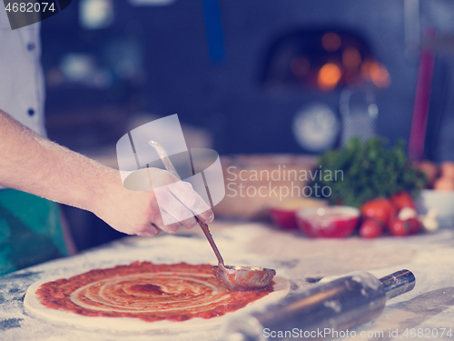 Image of Chef smearing pizza dough with ketchup