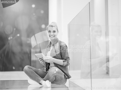 Image of young woman using tablet computer on the floor