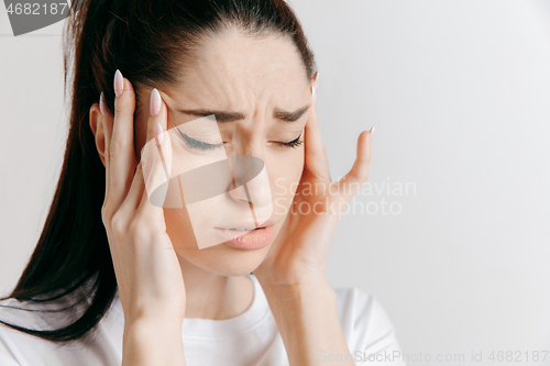 Image of Woman having headache. Isolated over gray background.