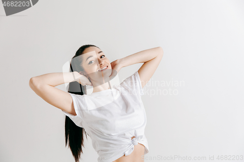 Image of The happy woman standing and smiling against gray background.