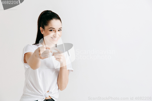 Image of The happy woman standing and smiling against gray background.
