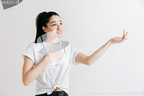 Image of The happy woman standing and smiling against gray background.