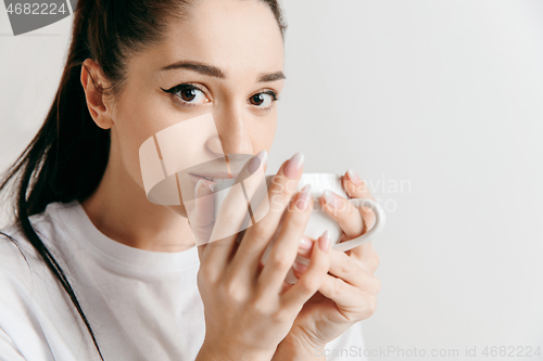 Image of Taking a coffee break. Handsome young man holding coffee cup while standing against gray background