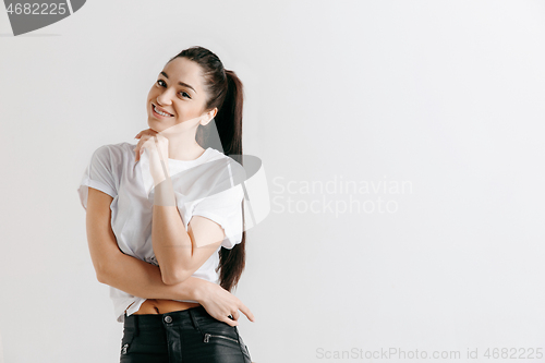 Image of The happy woman standing and smiling against gray background.