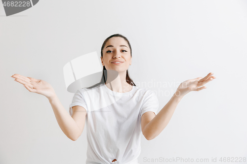 Image of The happy woman standing and smiling against gray background.