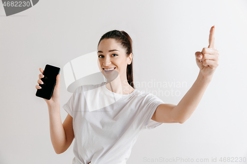 Image of Portrait of a confident casual girl showing blank screen of mobile phone