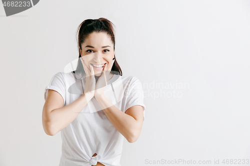 Image of The happy woman standing and smiling against gray background.