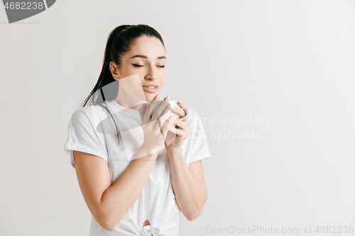 Image of Taking a coffee break. Handsome young man holding coffee cup while standing against gray background