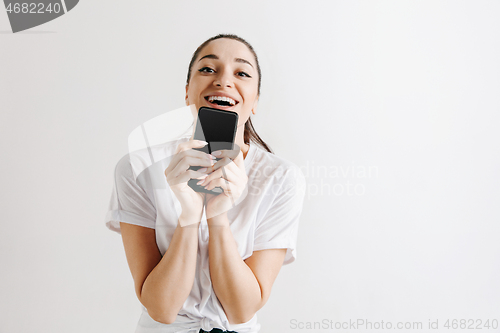 Image of Portrait of a confident casual girl showing blank screen of mobile phone