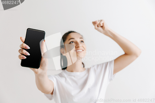 Image of Portrait of a confident casual girl showing blank screen of mobile phone