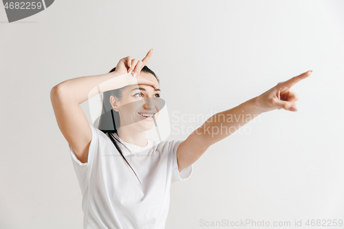 Image of Losers go home. Portrait of woman showing loser sign over forehead