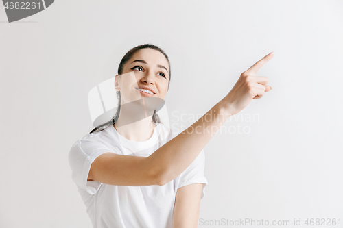 Image of The happy woman standing and smiling against gray background.