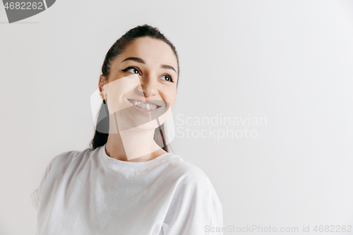 Image of The happy woman standing and smiling against gray background.