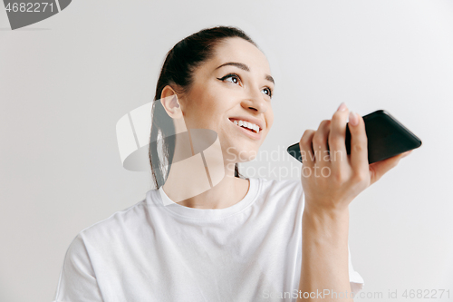 Image of Indoor portrait of attractive young woman holding blank smartphone