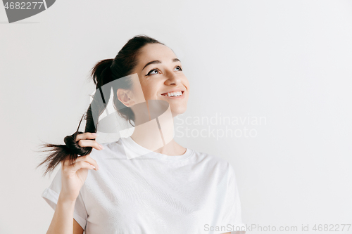 Image of The happy woman standing and smiling against gray background.