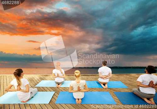 Image of group of people making yoga exercises outdoors