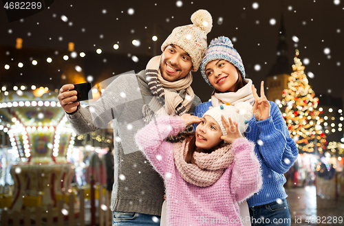 Image of happy family taking selfie at christmas market