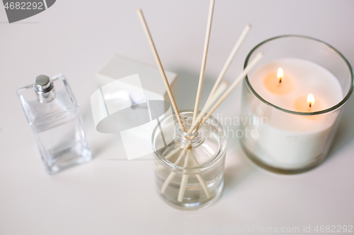 Image of aroma reed diffuser, burning candle and perfume