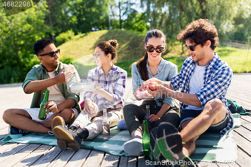 Image of happy friends having picnic at summer park