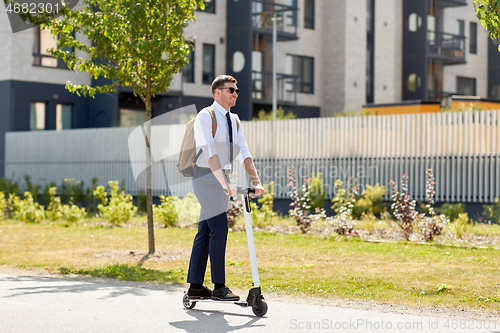 Image of businessman with backpack riding electric scooter