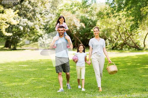 Image of family with picnic basket walking in summer park