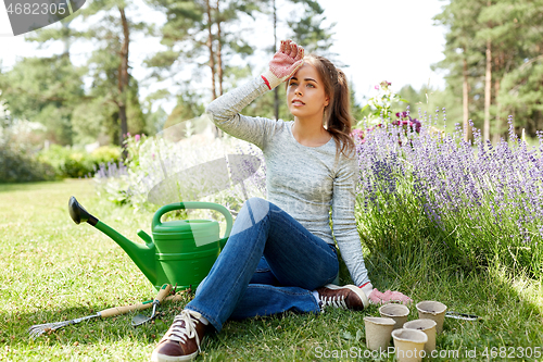 Image of tired young woman with garden tools in summer