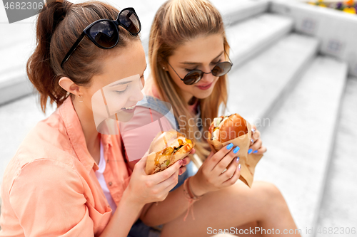 Image of teenage girls or friends eating burgers outdoors