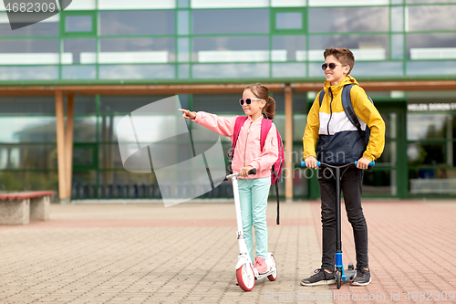 Image of happy school children with backpacks and scooters