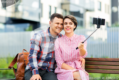 Image of family couple with stroller taking selfie in city