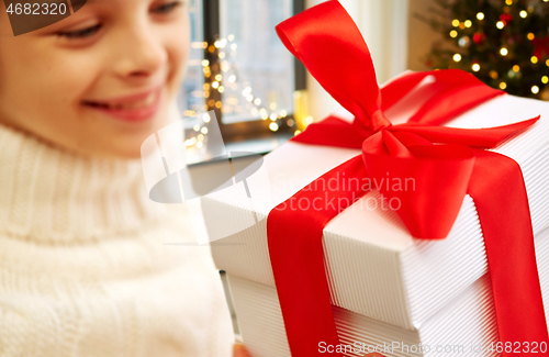 Image of happy beautiful girl with christmas gift at home