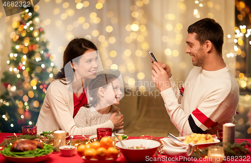 Image of happy family taking picture at christmas dinner