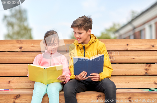 Image of school children reading books sitting on bench