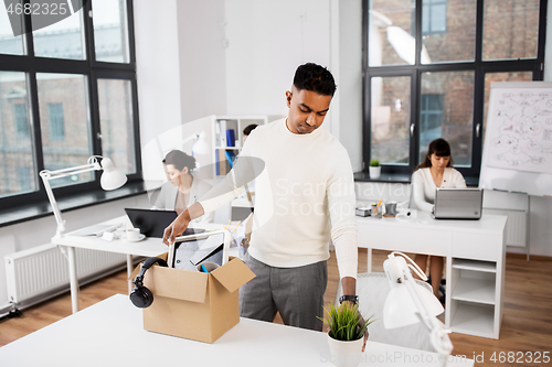 Image of sad fired office worker packing personal stuff