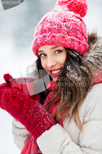 Image of happy young woman with tea cup in winter park