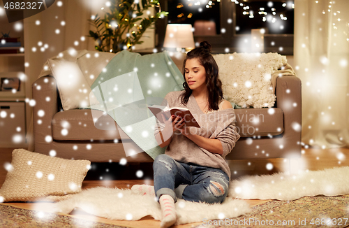 Image of happy young woman reading book at home