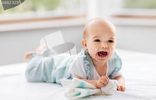 Image of crying baby girl lying on white blanket