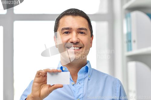 Image of smiling businessman with business card at office