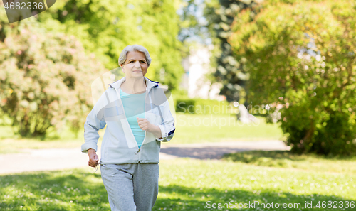 Image of senior woman running along summer park