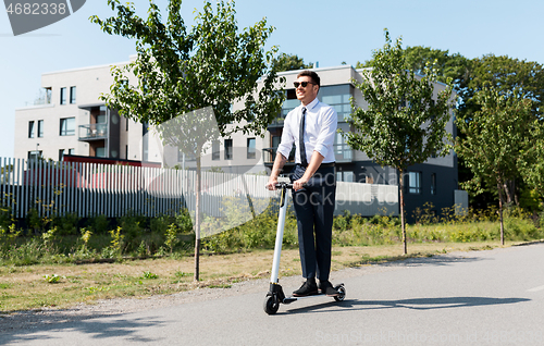 Image of young businessman riding electric scooter outdoors