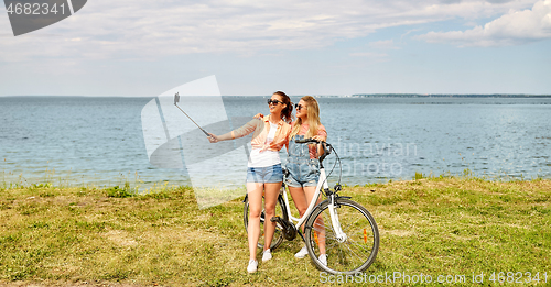 Image of teenage girls with bicycle taking selfie in summer