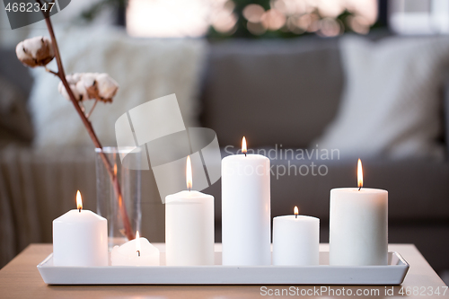 Image of burning white candles on table at cozy home