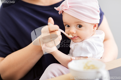 Image of middle-aged mother feeding baby daughter at home