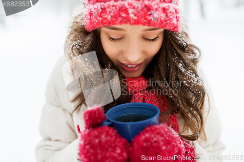 Image of happy young woman with tea cup in winter