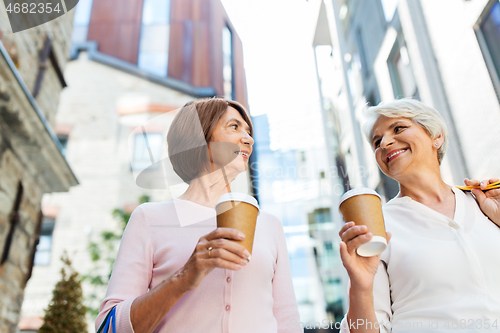 Image of senior women with shopping bags and coffee in city