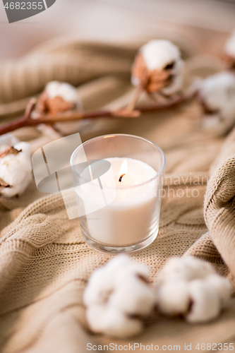 Image of burning candle and cotton flower on blanket