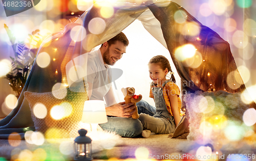 Image of happy family playing with toy in kids tent at home