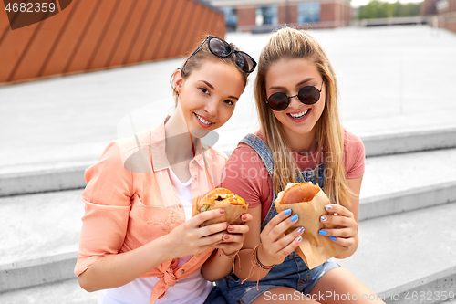 Image of teenage girls or friends eating burgers outdoors
