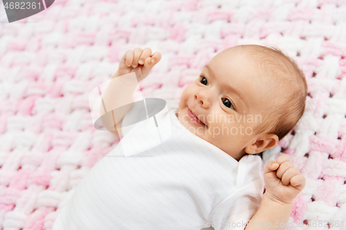 Image of sweet baby girl lying on knitted plush blanket